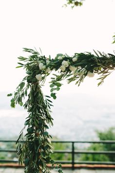 the wedding arch is decorated with greenery and white flowers on it's side