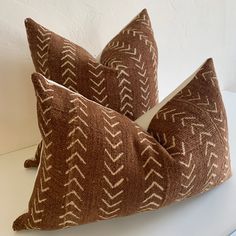 two brown and white pillows sitting on top of a white table next to each other