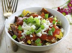 a close up of a bowl of food on a table with flowers in the background