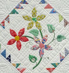 a quilted wall hanging with colorful flowers and leaves on it's center piece