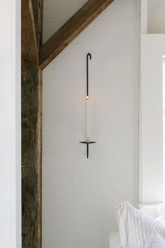 a white bed sitting under a wooden beam next to a wall mounted candle on it's side