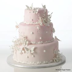 a three tiered pink cake with white flowers on it