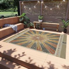 an outdoor area with wooden benches and plants on the deck, surrounded by string lights