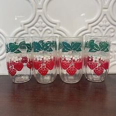 four red and green glasses sitting on top of a wooden table