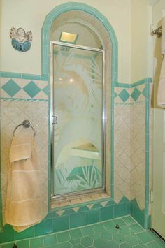 a bathroom with green and white tiles on the floor, shower stall and towel rack