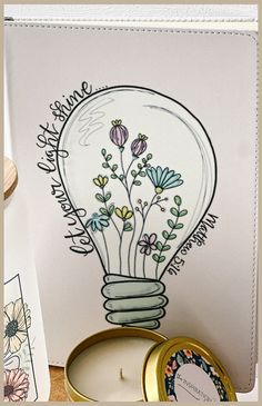 a card with flowers in a light bulb surrounded by other greeting cards and candle holders