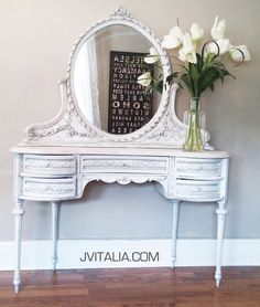 a white vanity with flowers on it and a mirror