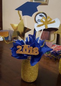 a table topped with two vases filled with cake toppers and blue ribbon decorations