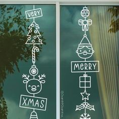 two windows with christmas decorations drawn on the glass and behind them is a green tree