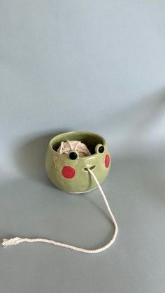 a green bowl with red dots on it and a white string attached to the bottom