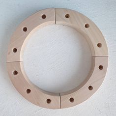 a circular wooden object with holes in the center on a white wall background, made out of plywood planks