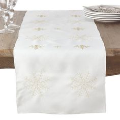 a white table runner with gold snowflakes on it and place settings next to it