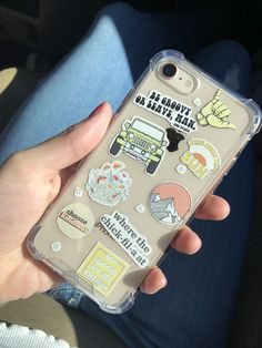 a person holding an iphone case with stickers on it