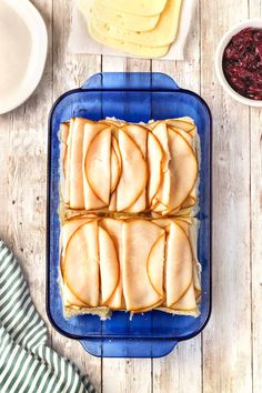 a blue plate topped with slices of fruit covered in icing next to bowls of cranberry sauce