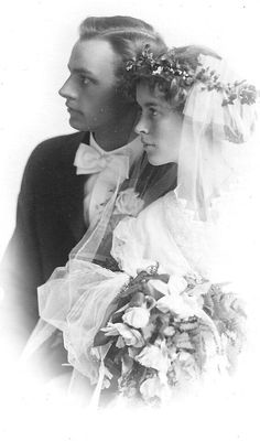 an old black and white photo of a man and woman in wedding attire holding each other