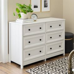 a white dresser sitting in a bedroom next to a window with pictures on the wall