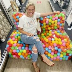 a woman is sitting on a chair made out of gummy balls in a store