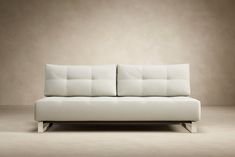 a white couch sitting on top of a wooden floor in front of a beige wall