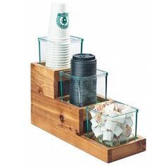 a wooden tray with cups and plates in it on top of a shelf next to another container