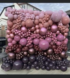 a bunch of balloons are stacked on top of each other in front of a house