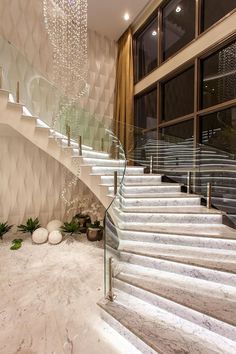 an elegant staircase with chandelier hanging from it's ceiling and marble steps