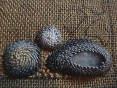 three crocheted rocks sitting on top of a piece of burlocked fabric