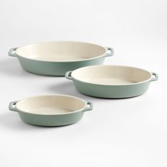 three green oval casserole dishes on a white background with no one around them