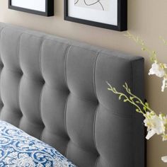 two framed pictures hang on the wall above a gray headboard with blue and white pillows