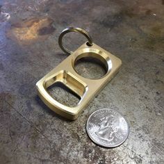 a metal keychain sitting on top of a table next to a coin