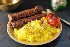 a plate with rice, meat and vegetables on it next to a small bowl full of other food