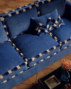 a blue couch sitting on top of a wooden floor next to a vase with flowers