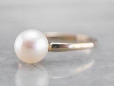 This pearl solitaire ring will be a classic for years to come! The pearl shimmers to perfection, with a glowing ghostly white hue. Crafted from 18 karat white gold, this ring is refined beauty at its very best! Metal: 18K White Gold Gem: Pearl Gem Measurements: 6.6 mm, Round Ring Size: 5 Marks: "18K" Stamped on the inside band Classic White Pearl Ring With Drop Detail, Minimalist Formal Pearl Drop Ring, White Solitaire Pearl Ring Fine Jewelry, White Solitaire Pearl Ring, Round Cut, White Solitaire Pearl Ring, Timeless White Round Cut Pearl Ring, Classic White Pearl Ring, White Timeless Round Cut Pearl Ring, White Akoya Pearl Ring With Pearl Drop