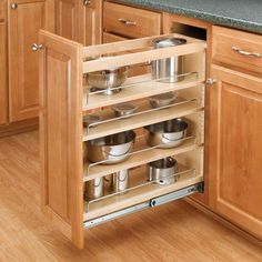 an open cabinet in a kitchen with pots and pans on the bottom shelf,