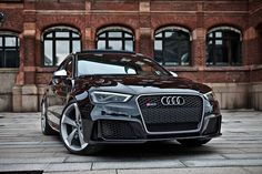 a black car parked in front of a brick building