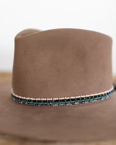 This hat band mixes beautiful faceted glass beads with brass accents to create a subtle sparkle to add to your hat. Material: Faceted glass beads & brass beads Dimensions: 21" beaded length Closure: Adjustable slide closure Color Options: Black, Gray, Beige, Blue Handmade by Crossbow in the mountains of Telluride, CO. Western Beaded Hat Bands, Seed Bead Hat Band Patterns, Diy Hat Band Ideas, Cowboy Hat Bands Diy, Beaded Hats Native American, Beaded Hat Brim, Burned Hats, Cowboy Hat Band, Hat Painting