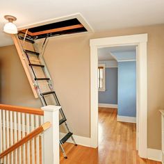 there is a ladder going up to the ceiling in this room with wood flooring