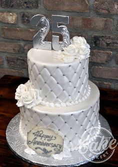 a white wedding cake decorated with flowers and the number twenty five on it's side