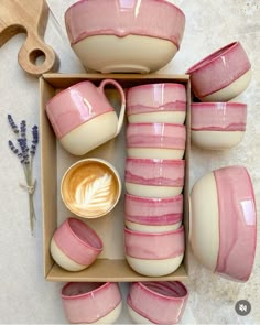 pink and white dishes with matching cups are arranged in a box next to lavenders