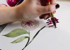 a woman's hand holding a pen and drawing flowers