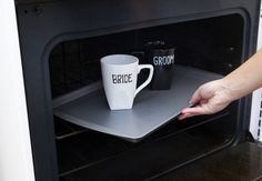 two coffee mugs are placed in an oven