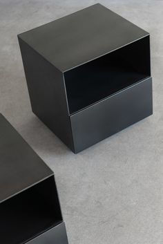 three black boxes sitting on top of a cement floor