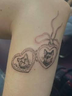 a woman's arm with two cats in heart shaped lockes on the wrist