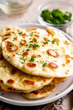 three pita breads on a white plate with some green garnishes