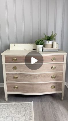 a white dresser with drawers and plants on top in a room that is painted gray