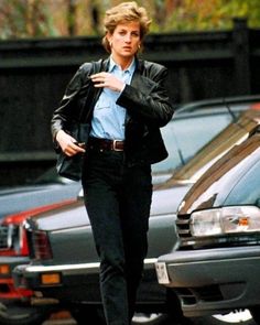 a man walking down the street with his hand on his hip while wearing a leather jacket