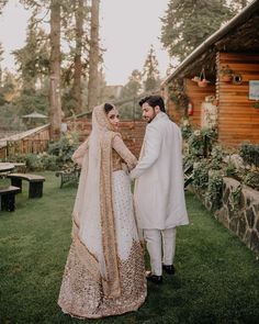 a man and woman standing next to each other in front of a wooden building with trees