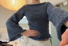 a woman wearing a blue sweater is holding her hands on her hips and looking at the camera