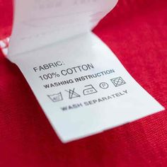 a red shirt with a white label on it that says fabric 100 % cotton washing instruction