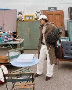 a man is walking through an outdoor flea market with furniture and other items in the background