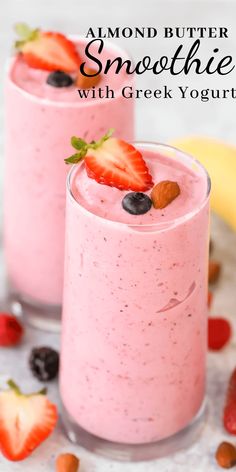 two glasses filled with smoothie and topped with strawberries, blueberries, and almonds